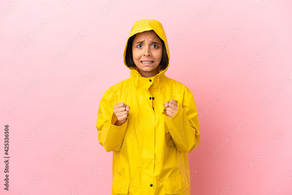 Young latin woman wearing a rainproof coat over isolated background frustrated by a bad situation Young latin woman wearing a rainproof coat over isolated background frustrated by a bad situation