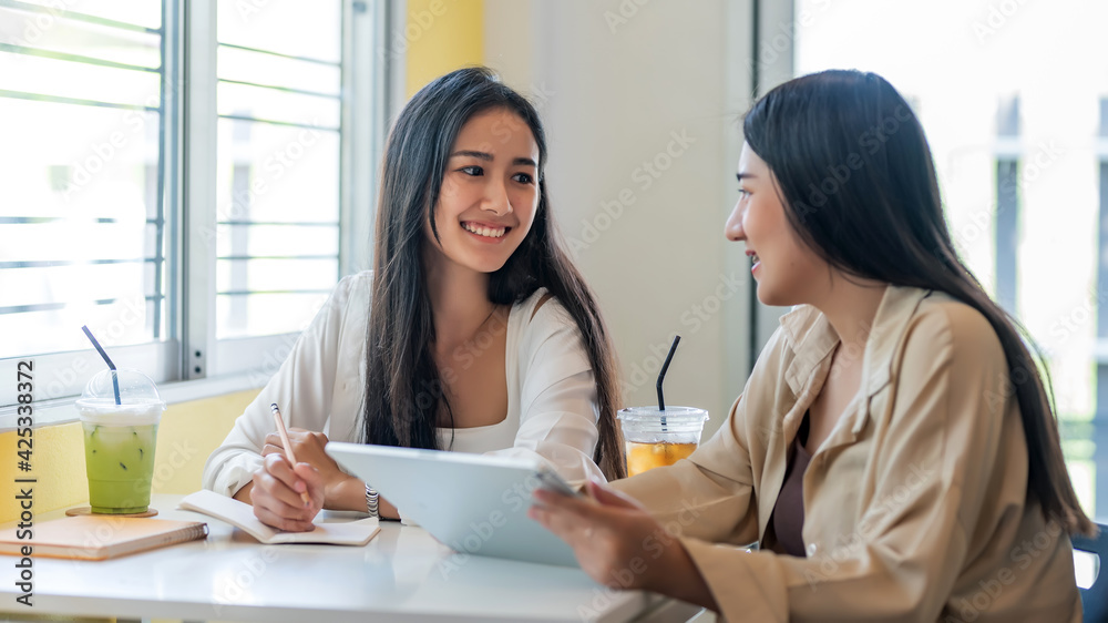 Young Asian businesswoman are happy to work together using a tablet at the café. Young Asian businesswoman are happy to work together using a tablet at the café.