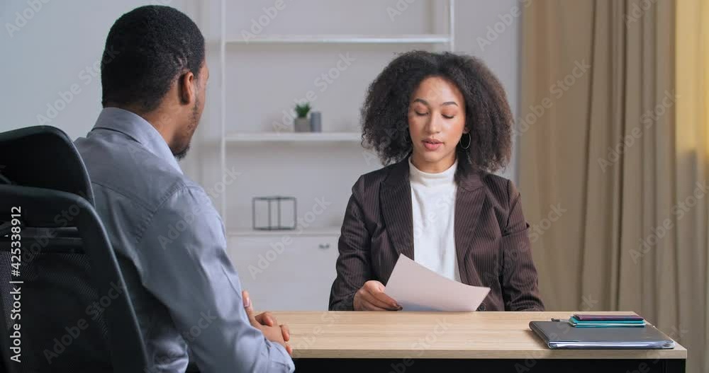 Unrecognizable afro american businessman sits in office at table talking to managers female secretary partner discussing deal new project businesswomen gives paper documents contract for signature Unrecognizable afro american businessman sits in office at table talking to managers female secretary partner discussing deal new project businesswomen gives paper documents contract for signature