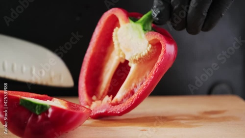 Close-up, hand of unrecognizable male chef cutting red pepper with sharp knife. Cutting pepper with a knife. Cutting vegetables