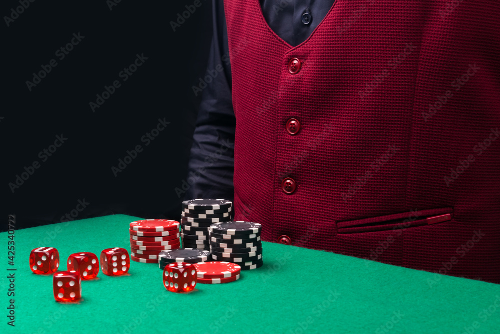 on the gaming table, dice and chips for gambling, on the dark background of the torso of the working staff in the casino on the gaming table, dice and chips for gambling, on the dark background of the torso of the working staff in the casino