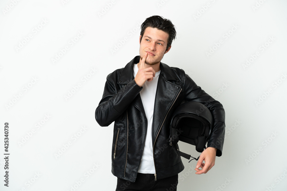 Russian man with a motorcycle helmet isolated on white background having doubts while looking up Russian man with a motorcycle helmet isolated on white background having doubts while looking up