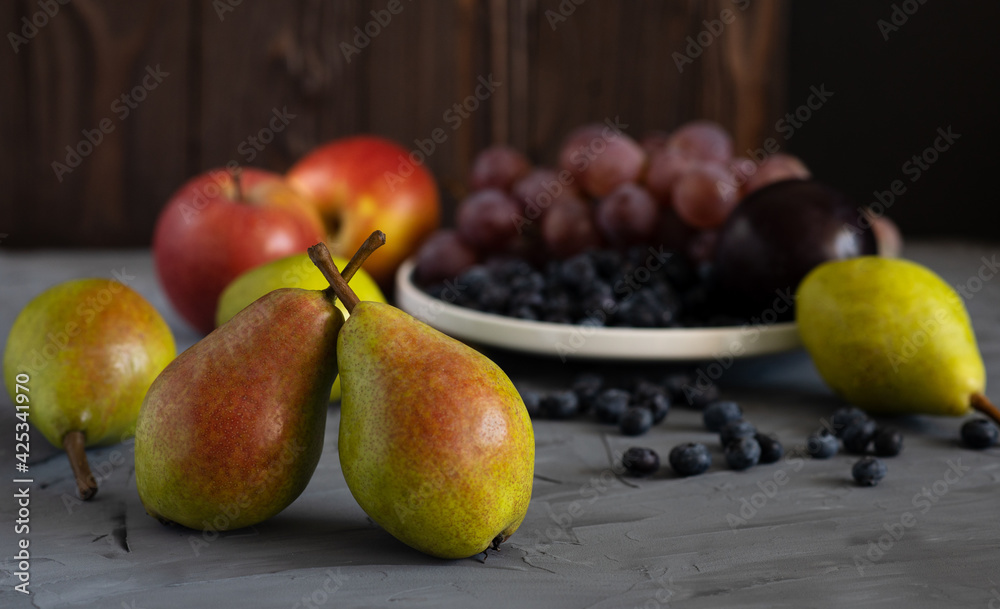still life of fresh fruits on a gray background, assorted pears, apples, grapes, blueberries close-up still life of fresh fruits on a gray background, assorted pears, apples, grapes, blueberries close-up