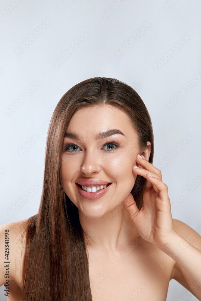 Beauty face. Smiling woman touching healthy skin portrait. Beautiful happy girl model with fresh facial skin and natural makeup on grey background. Skin care concept Beauty face. Smiling woman touching healthy skin portrait. Beautiful happy girl model with fresh facial skin and natural makeup on grey background. Skin care concept