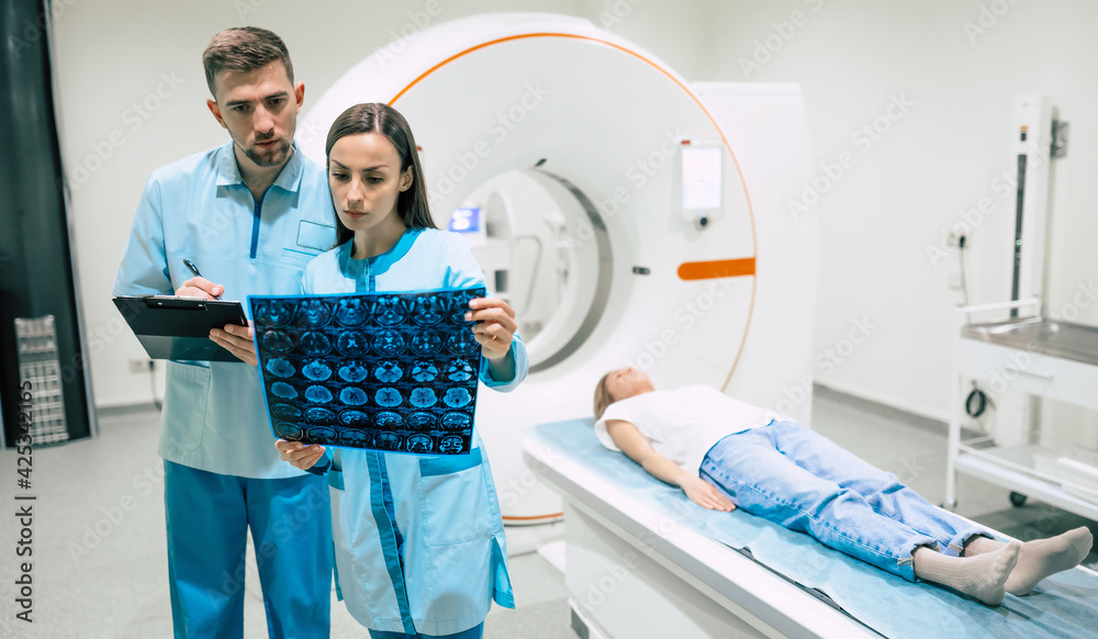 Confident experienced professional oncologist looking at the magnetic resonance imaging scan results of the human brain Confident experienced professional oncologist looking at the magnetic resonance imaging scan results of the human brain