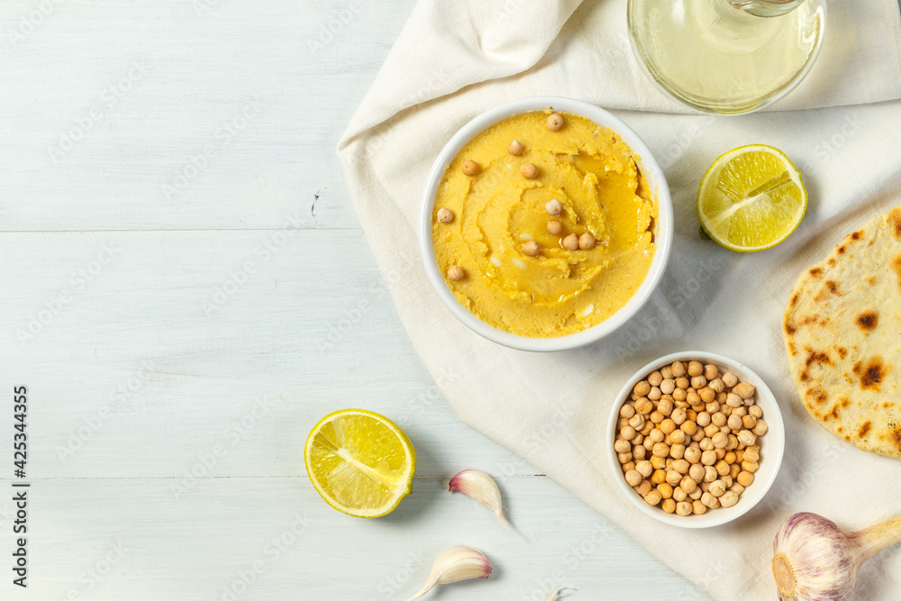hummus in a small bowl on a gray wooden surface with tortilla, chickpeas, garlic and lime. Overhead, with copy space hummus in a small bowl on a gray wooden surface with tortilla, chickpeas, garlic and lime. Overhead, with copy space