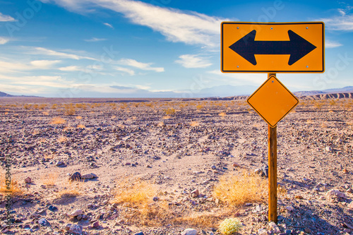 Directional sign in the desert with scenic blue sky and wide horizon. Concept for trip, freedom and transportation.