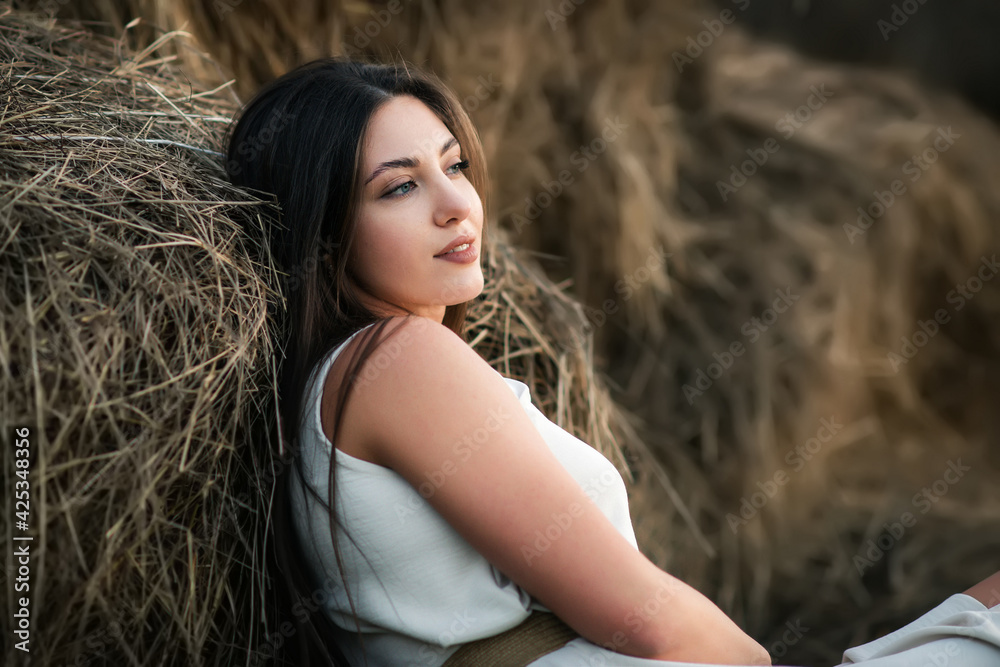 Natural beauty young woman sits on the hay. Outdoor woman portrait Natural beauty young woman sits on the hay. Outdoor woman portrait
