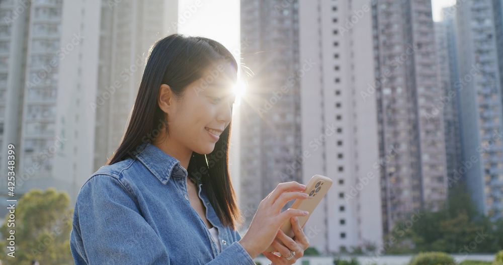 Woman look at the cellphone with sunlight flare in city
