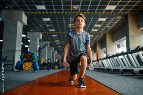 Boy doing exercise with dumbbells in gym