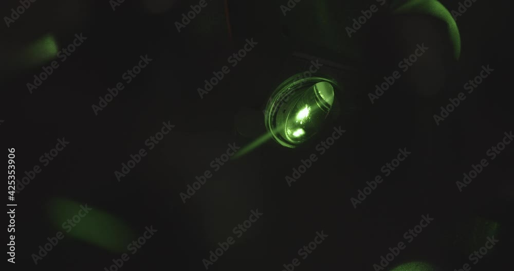 Green neon light projector with light flashing in dark room,close up shot. Party in night club.