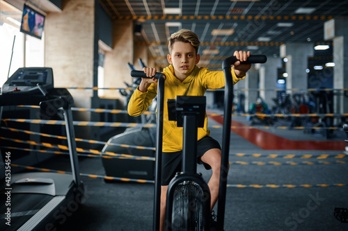 Child on exercise machine, training in gym