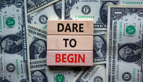 Dare to begin symbol. Wooden blocks with words 'Dare to begin'. Beautiful background from dollar bills. Business, dare to begin concept, copy space.