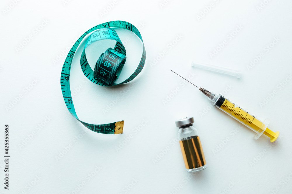 lipolytic and syringe on a white background next to a measuring tape ...