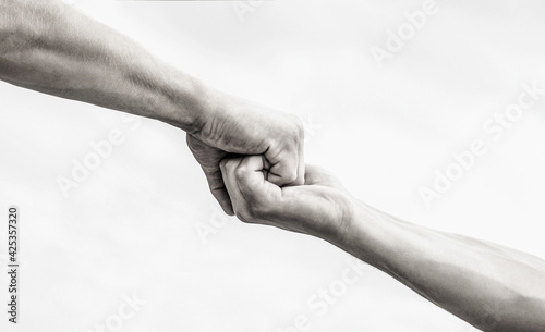 Giving a helping hand. Hands of man and woman on sky background. Lending a helping hand. Hands of man and woman reaching to each other, support. Black and white