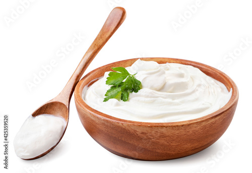 Sour cream in a wooden plate and spoon on a white background. Isolated