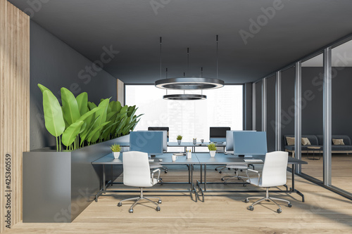 Dark modern minimalist office interior with desks and computer monitor