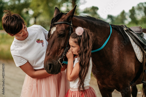 Child therapy for a walk with a horse. Emotional contact with the horse. Walk mother and daughter in the summer in the park with a horse.