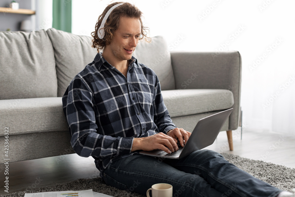 Man In Headphones Using Laptop Working Online Sitting At Home Man In Headphones Using Laptop Working Online Sitting At Home