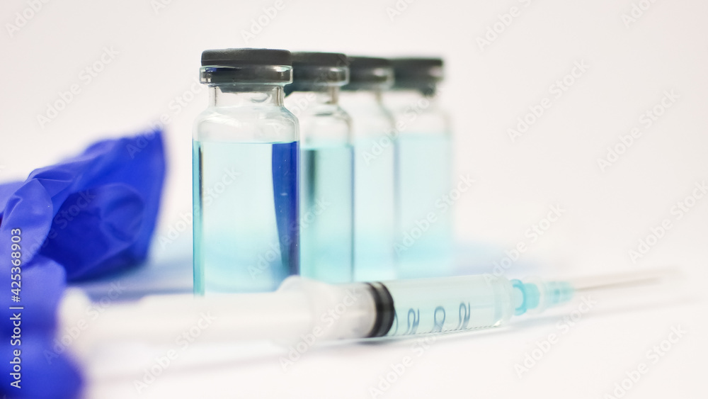 Vial vaccine, glass ampoules and a syringe with medical protective gloves on white background, global vaccination concept Vial vaccine, glass ampoules and a syringe with medical protective gloves on white background, global vaccination concept
