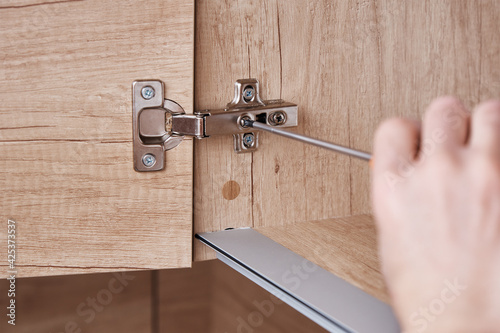 Hand screwing door hinge on kitchen cabinet photo