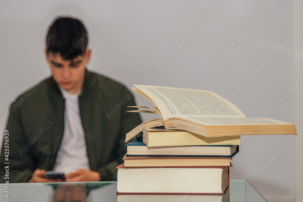 books in the foreground with student with phone books in the foreground with student with phone