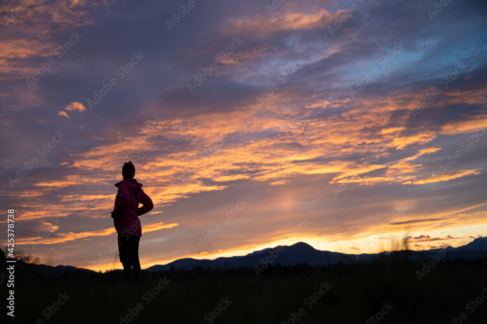 Woman standing on and ascent in beautiful nature under glowing evening sky