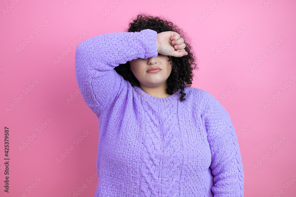 Young beautiful woman wearing casual sweater over isolated pink background covering eyes with arm smiling cheerful and funny. Blind concept. Young beautiful woman wearing casual sweater over isolated pink background covering eyes with arm smiling cheerful and funny. Blind concept.