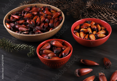 Typical araucaria seeds used as a condiment in Brazilian cuisine in winter. Brazilian pinion nuts in brown and red wooden bowl on gray wooden background