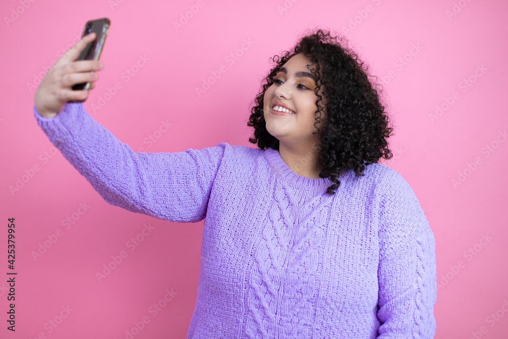 Young beautiful woman wearing casual sweater over isolated pink background taking a selfie