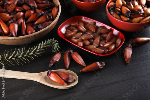 Typical araucaria seeds used as a condiment in Brazilian cuisine in winter. Brazilian pinion nuts in brown and red wooden bowl on gray wooden background photo