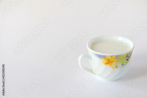 White mug with milk on a white background. White mug with flower print