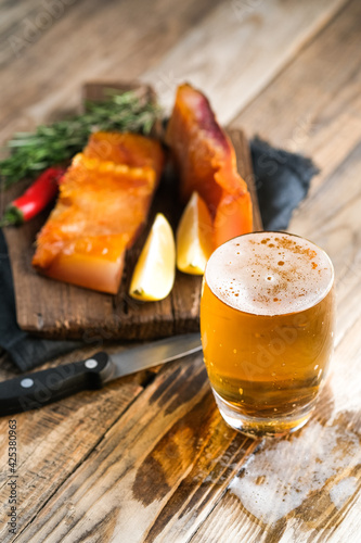 Glass of beer and smoked fish on a rustic background.