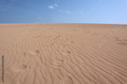 Footsteps on a beige sand dune in Taroa la guajira colombia with a blue sky, walking in the heat in a dry and sunny day in the desert 