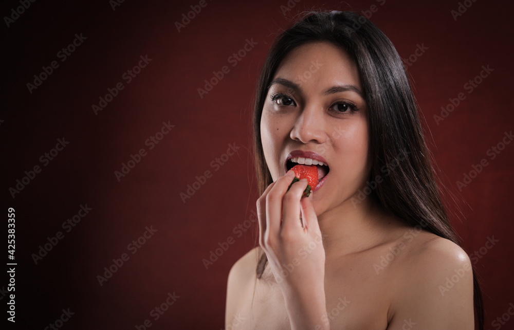 Young pretty woman bites into a strawberry - studio photography Young pretty woman bites into a strawberry - studio photography