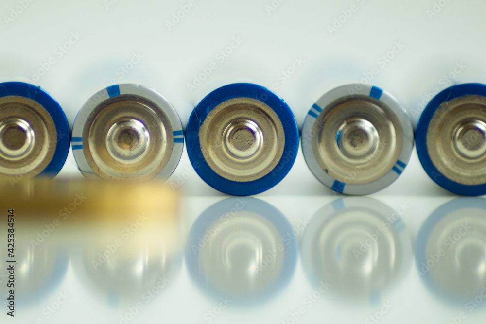 set of batteries, coins and light bulb on white background
