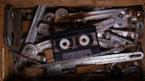 An old tape cassette in front of a background with full of old tools.