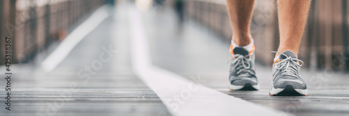 Walking exercise outside on city street banner. Running shoes closeup of man on outdoor walk training jogging. Active athlete on Brooklyn bridge, New York City lifestyle. Outdoor fitness panoramic.