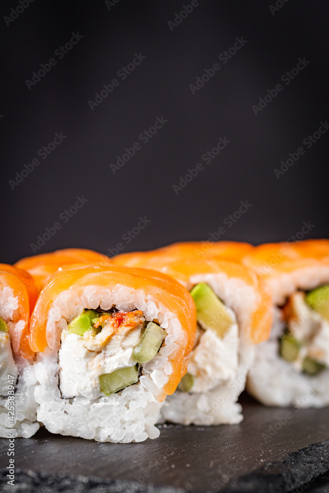appetizing sushi roll philadelphia with avocado cheese eel cucumber and salmon on a black stone plate appetizing sushi roll philadelphia with avocado cheese eel cucumber and salmon on a black stone plate