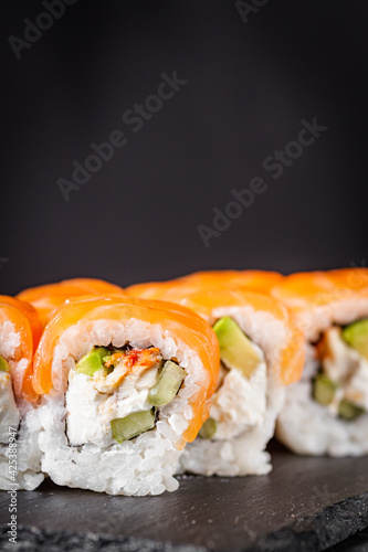 appetizing sushi roll philadelphia with avocado cheese eel cucumber and salmon on a black stone plate