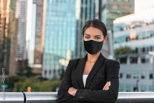 Asian business woman or real estate agent confident portrait wearing face mask for coronavirus prevention in urban city background.