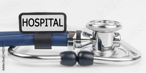 On the white surface lies a stethoscope with a plate with the inscription - HOSPITAL
