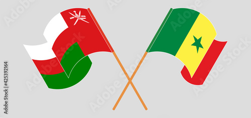 Crossed and waving flags of Oman and Senegal