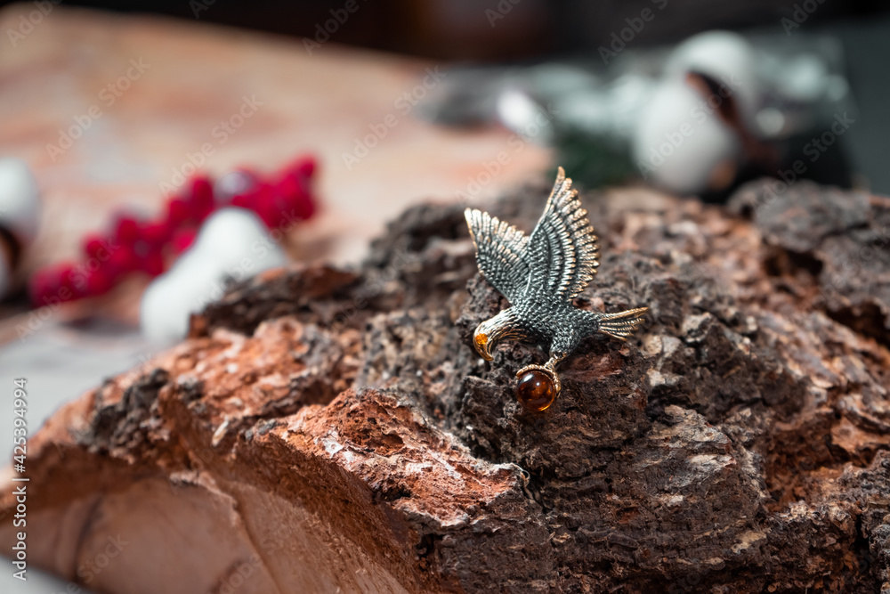 Decoration in the form of a flying eagle of bronze and amber on a wooden background