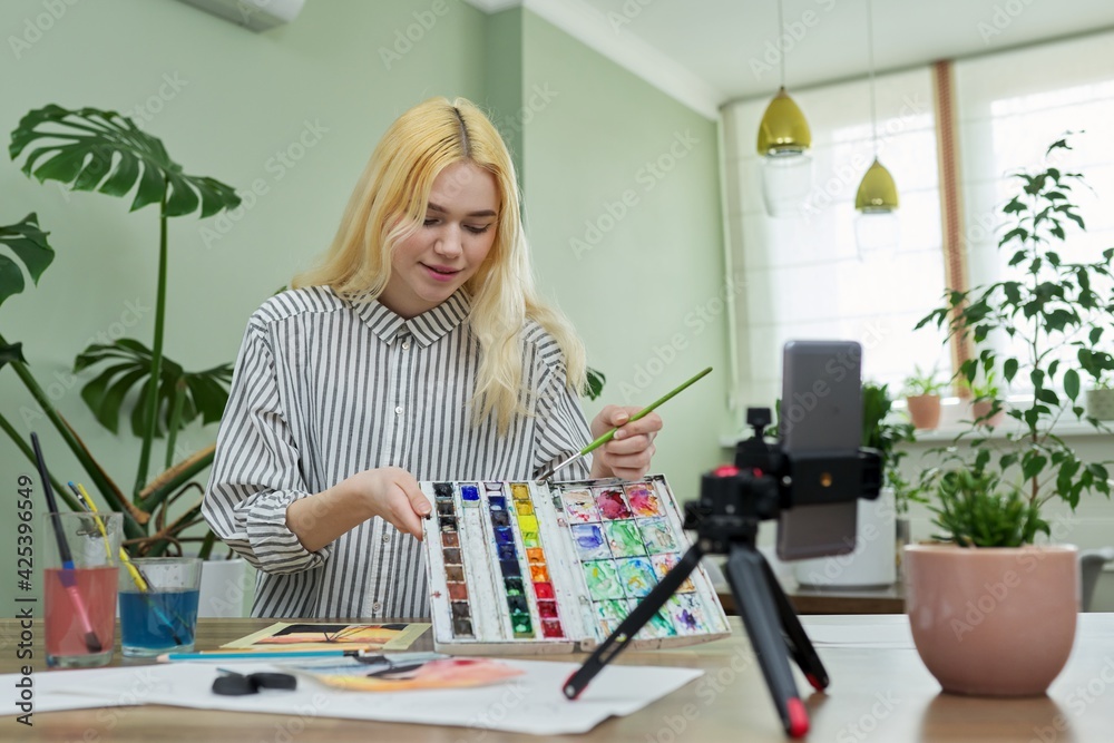 Teenage girl recording video drawing lesson using smartphone on tripod Teenage girl recording video drawing lesson using smartphone on tripod