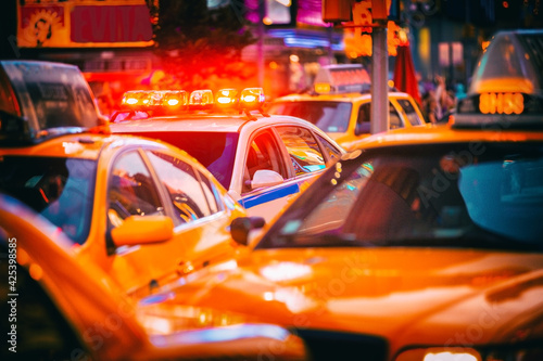 Fotografie New York City Police patrol car flashing beacon siren lights in busy NYC traffic jam with yellow taxi cabs cars