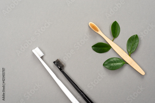 Natural eco friendly bamboo toothbrush and plastic toothbrush on gray background. Choose a plastic or wooden toothbrush. Recycling concept, no waste, no plastic, top view
