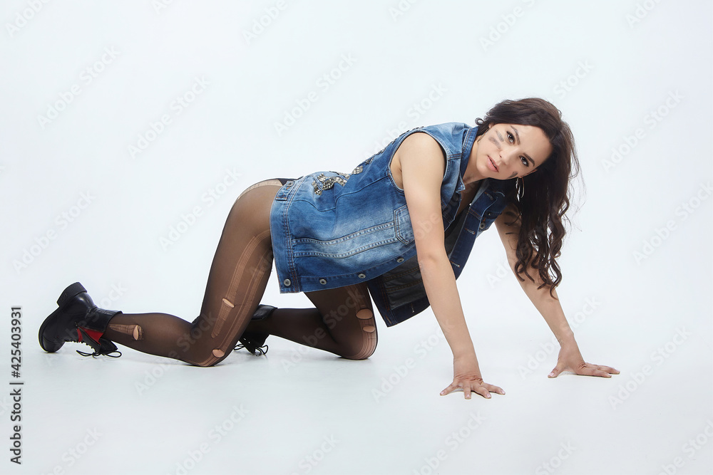 sexy woman in torn tights and denim jacket poses in the studio on a white background sexy woman in torn tights and denim jacket poses in the studio on a white background