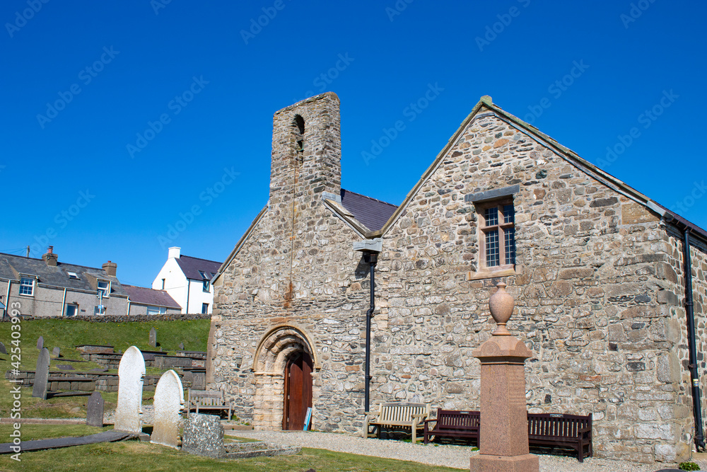 Aberdaron village, Wales. Historic church of Saint Hywyn. Beautiful old landmark which was a place to worship for pilgrims heading to Bardsey island in medieval times. Blue sky and copy space.