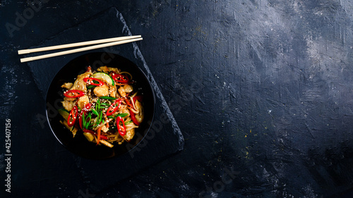 Quadro em tela Udon stir fry noodles with chicken and vegetables on black background